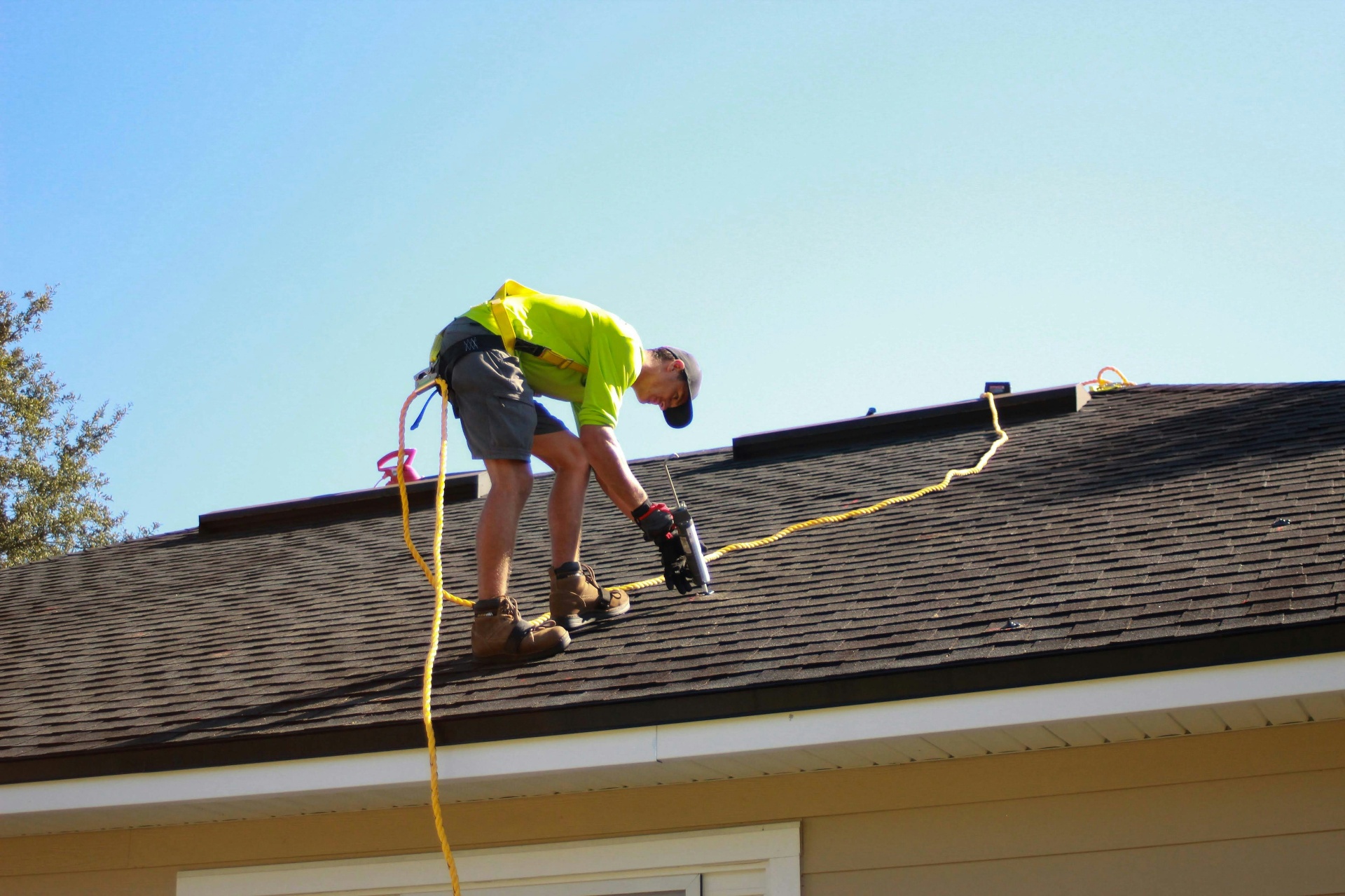 Roofer installing asphalt shingles with nailer — on-page roofing SEO optimization